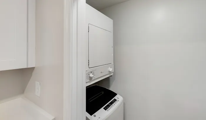 Compact laundry area with stacked washer and dryer, offering functional and space-saving convenience for modern living.Your spacious kitchen offers generous square footage with room for multiple people and all your cooking essentials. | The Royal Crest | Apartment in,North Andover MA