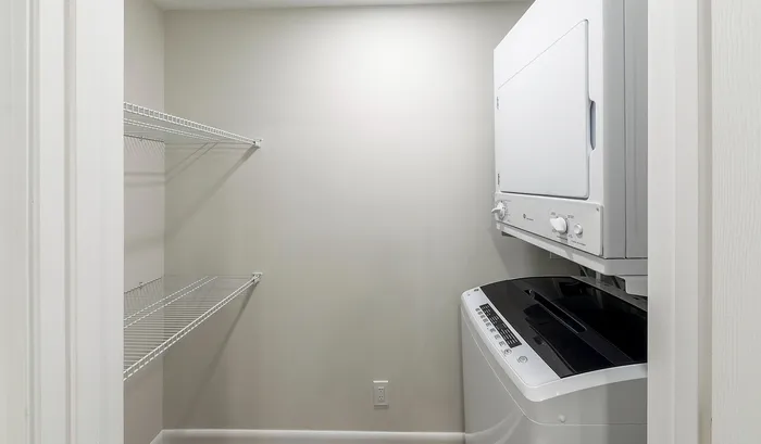 Modern laundry room featuring a convenient stacked washer and dryer set with ample shelving for storage.Your spacious kitchen offers generous square footage with room for multiple people and all your cooking essentials. | The Royal Crest | Apartment in,North Andover MA