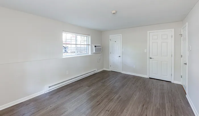 Bright, spacious room with elegant wood flooring, large window with natural light, and sleek white walls, offering a versatile living space.Your spacious kitchen offers generous square footage with room for multiple people and all your cooking essentials. | The Royal Crest | Apartment in,North Andover MA