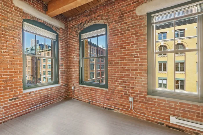 Your charming loft apartment features exposed brick walls and large windows that fill the space with abundant natural light overlooking a vibrant urban street. | 381 Congress Lofts | Apartments For Rent in Boston