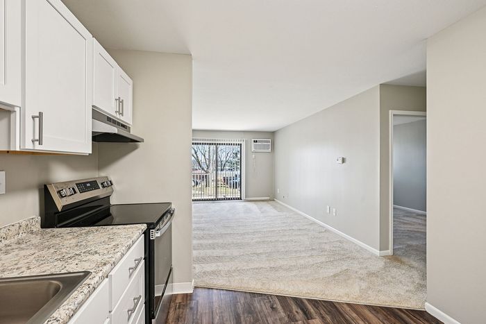 Chic apartment with sleek kitchen, modern appliances, and sunlit living area boasting floor-to-ceiling windows.
