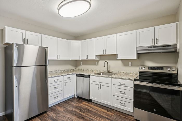 Modern kitchen with sleek stainless steel appliances, elegant white cabinetry, and granite countertops, perfect for culinary enthusiasts.