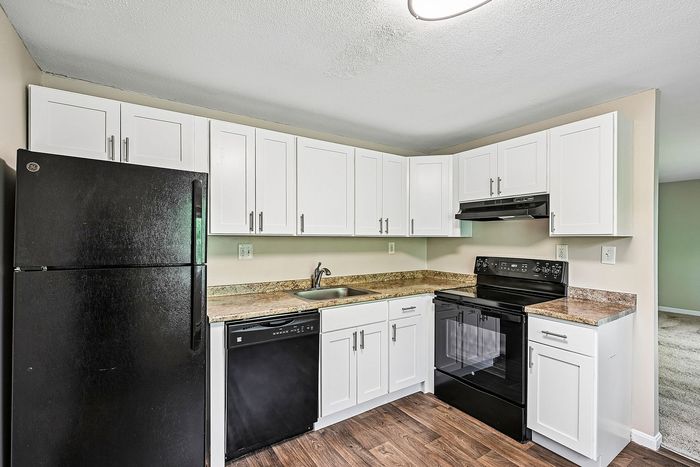 Modern kitchen with sleek black appliances, elegant white cabinetry, and stylish marble countertops.