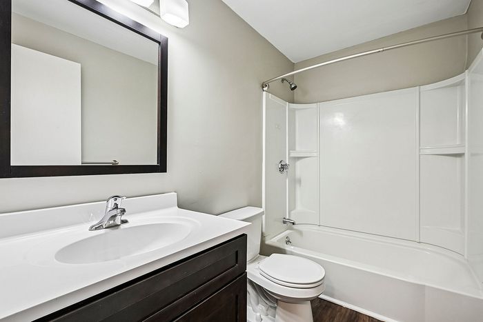 Modern bathroom featuring a sleek vanity with a large mirror and a pristine white bathtub, offering both style and comfort.