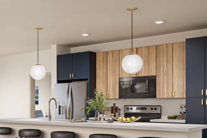 Princeton Wilmington Apartments | Modern kitchen with sleek appliances, stylish pendant lights, and a sophisticated blend of wood and navy cabinetry. | New Construction for Rent in Massachusetts
