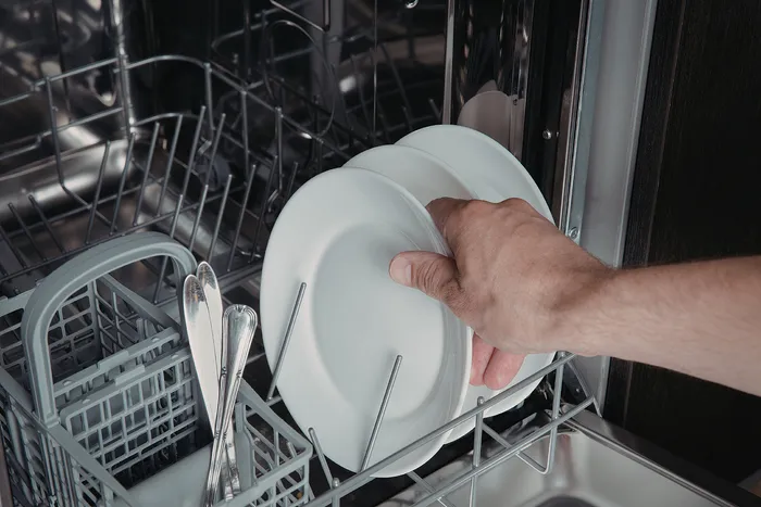 Modern dishwasher interior with silverware basket and plates, showcasing efficient kitchen convenience.