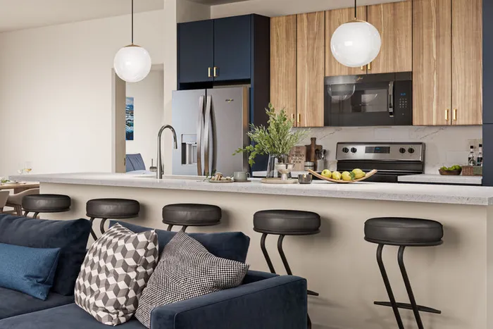 Luxurious open kitchen with sleek modern appliances, elegant pendant lighting, and stylish breakfast bar seating, perfect for entertaining.