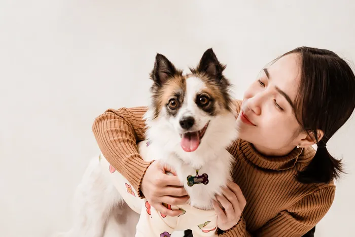 Heartwarming moment of a smiling woman hugging her adorable dog in a cozy setting.