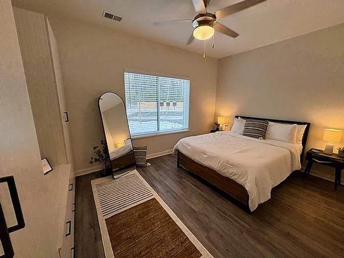 Bright and cozy bedroom with stylish hardwood floors, a comfortable bed, and a large window inviting natural light.