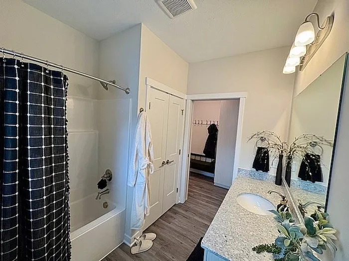 Modern bathroom with elegant lighting, granite countertop, and inviting ambiance, leading into a cozy hallway.