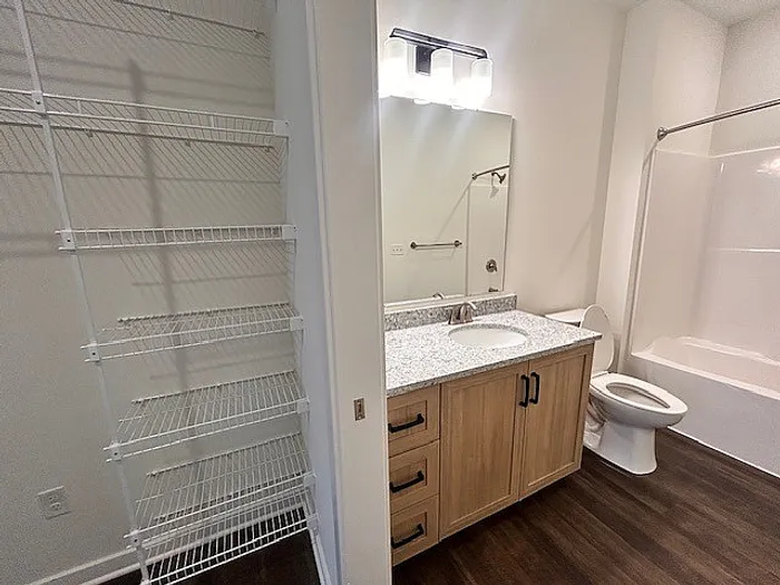 Elegant bathroom featuring a modern vanity with granite countertop, sleek shelving, and a pristine bathtub, perfect for relaxation.