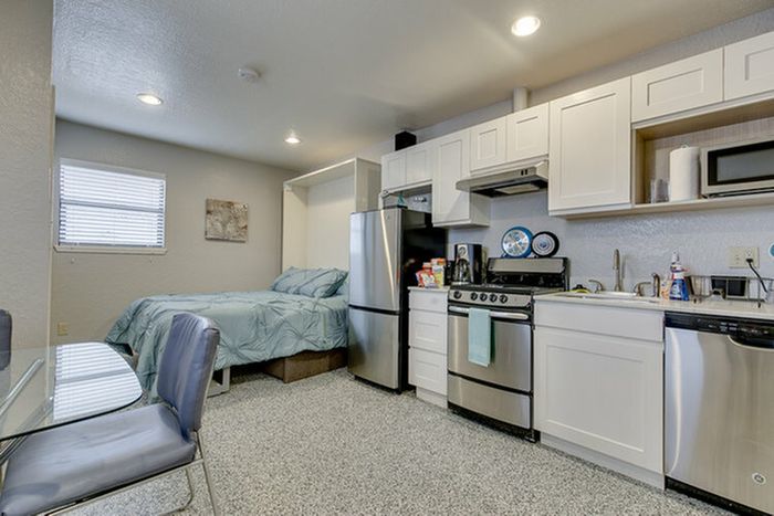Modern studio apartment with a cozy sleeping area, sleek kitchen, and dining space.
