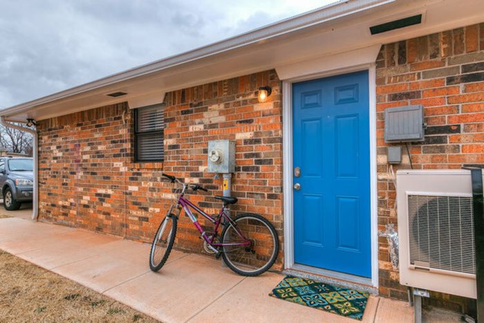 Inviting brick home exterior with a vibrant blue door and a bicycle parked alongside.