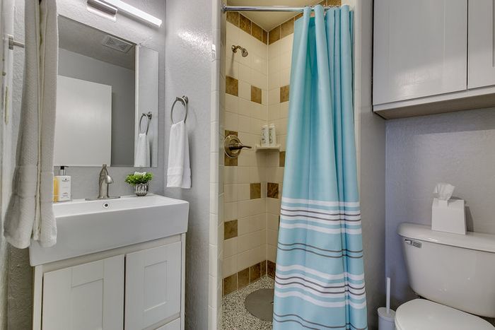Modern bathroom with stylish shower, vanity, and blue-striped curtain.