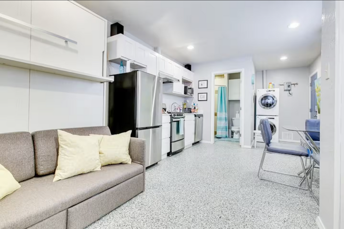 Efficient apartment interior featuring a modern kitchen, cozy seating area, and integrated laundry facilities.