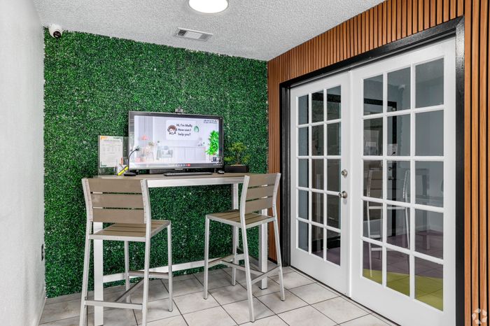Chic apartment nook with greenery accent wall, modern high table, and stylish chairs, perfect for a cozy workspace.