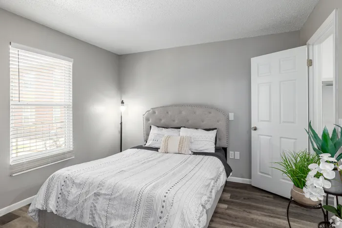 Cozy bedroom with elegant decor, featuring a plush bed, modern lamp, and natural light enhancing the stylish ambiance.