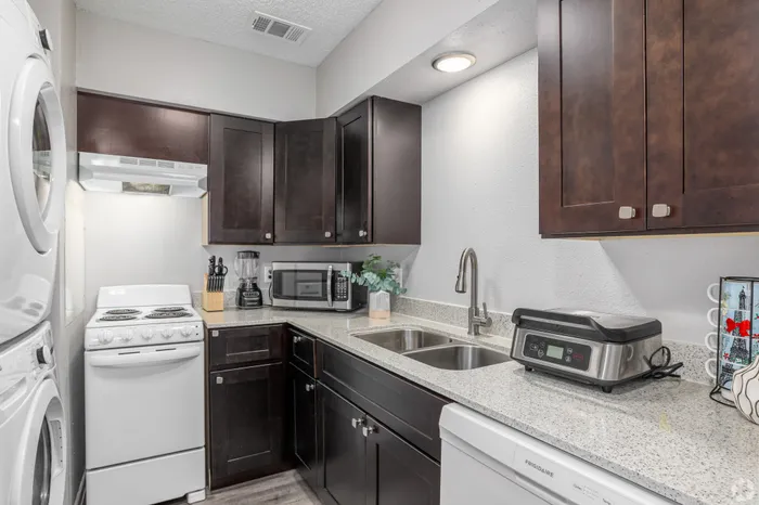 Contemporary kitchen with sleek dark wood cabinets, modern appliances, and elegant granite countertops.