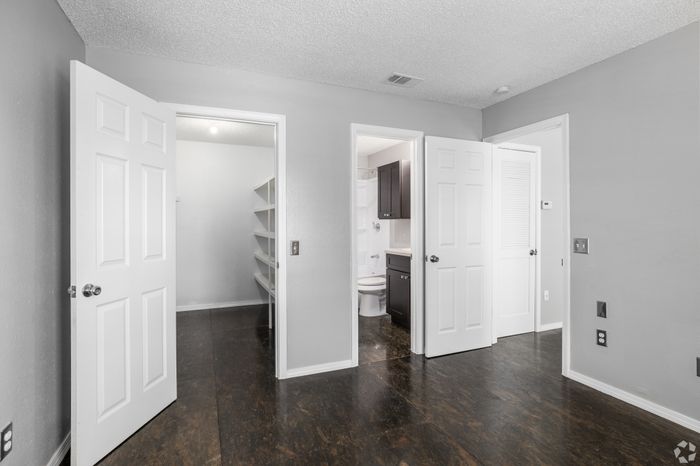 Bright and modern room featuring elegant wood flooring, spacious closet with built-in shelves, and access to a sleek bathroom with contemporary design.