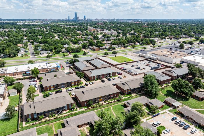 Charming apartment complex nestled in a lush neighborhood, offering proximity to city skyline views and ample parking.