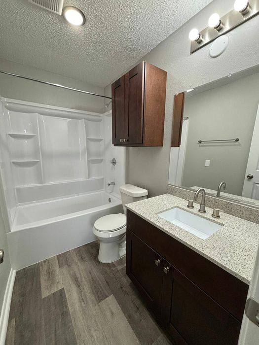 Modern bathroom with elegant dark wood cabinetry, sleek granite countertop, and luxurious bathtub, featuring stylish lighting and contemporary flooring.