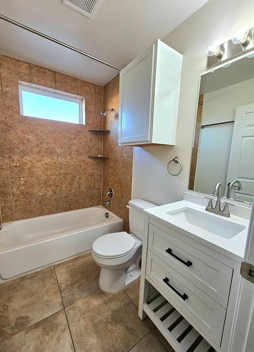 Modern bathroom featuring elegant tile work, a sleek white vanity, and natural light from a frosted window.