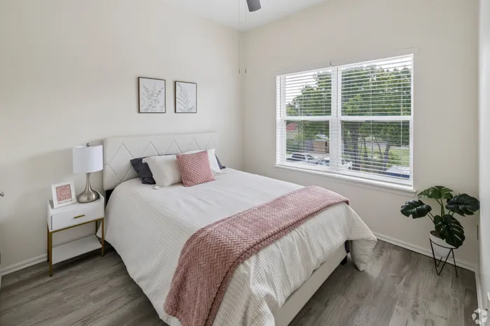 Bright and inviting bedroom featuring modern decor, large window with natural light, and cozy bedding.