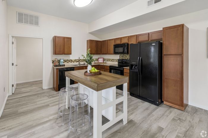 Modern kitchen with sleek wooden cabinetry, a central island with seating, and stylish stainless steel appliances.