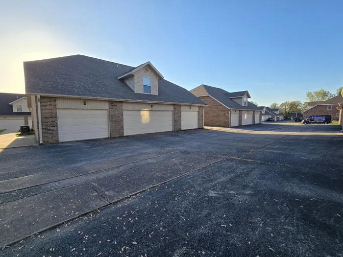 Charming residential complex with spacious garages and modern brick facade bathed in warm sunlight.