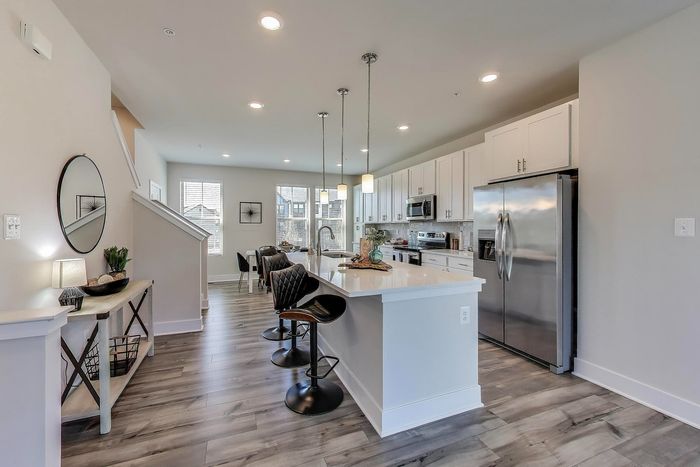 Modern open-concept kitchen and dining area with sleek white cabinets, stainless steel appliances, and elegant pendant lighting.
