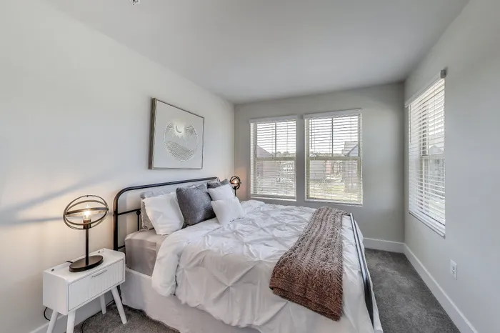 Inviting bedroom with ample natural light, cozy bedding, and modern d&eacute;cor, perfect for relaxation.