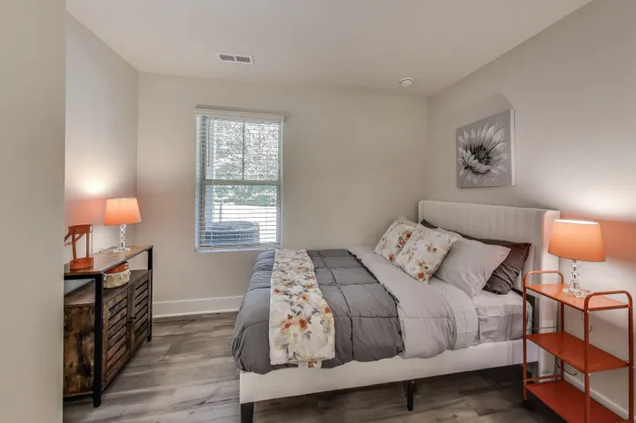 Cozy bedroom with elegant decor, featuring a plush bed, warm lighting, and a large window inviting natural light.