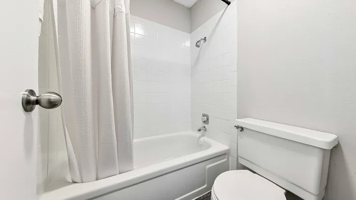 Minimalist bathroom featuring a white bathtub, shower, and modern fixtures.