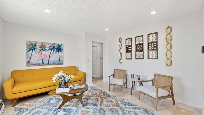 Bright living room with a stylish yellow sofa, colorful palm tree artwork, and modern decor.