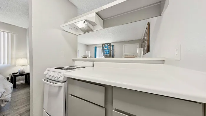 Bright, modern kitchen with white cabinetry, electric stove, and ambient lighting.