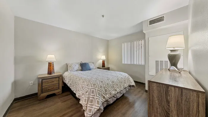 Elegant bedroom with a queen-size bed, stylish lamps, and modern wooden furniture.