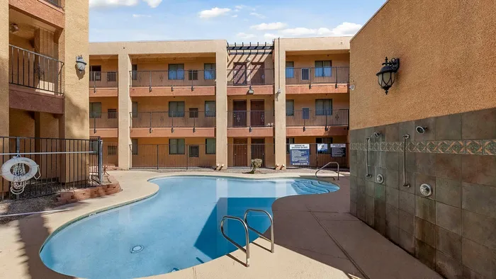 Modern apartment complex featuring a central swimming pool surrounded by a sunlit courtyard.