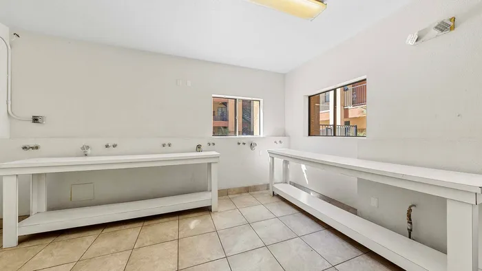 Sunlit laundry room with spacious counter space and tiled flooring.