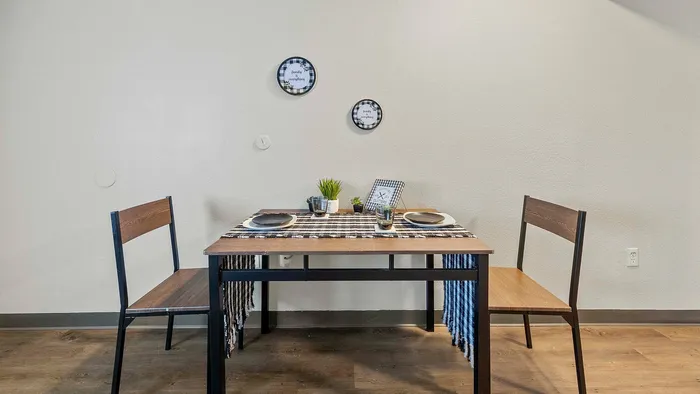 Cozy dining nook featuring a wooden table set for two, with decorative plates, cups, and plants.