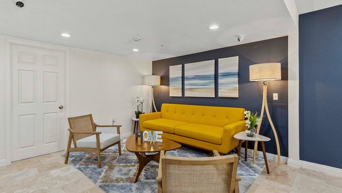 Contemporary living room with a vibrant yellow sofa, stylish art, and a cozy ambience.