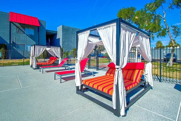 Vibrant outdoor lounge area with stylish cabanas and sun beds under a clear blue sky.