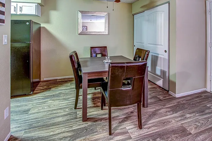 Sleek dining area with a dark wooden table, four leather chairs, and modern flooring.