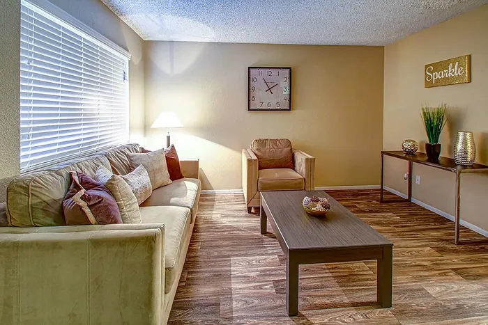 Inviting living room with stylish decor, plush sofa, armchair, and wooden coffee table under warm lighting.