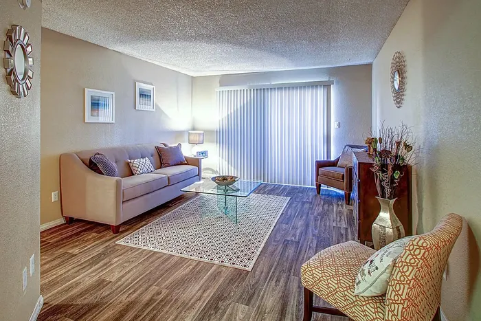 Inviting living room with stylish decor, featuring a beige sofa, glass coffee table, and warm lighting.