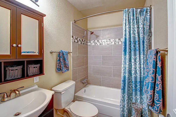 Charming bathroom with a stylish shower, vanity with mirror, and blue-patterned accents.