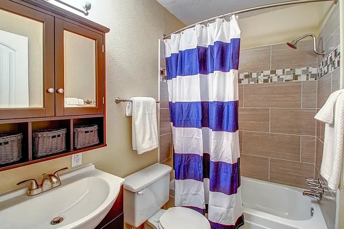 Modern bathroom with stylish cabinetry, striped shower curtain, and sleek fixtures.