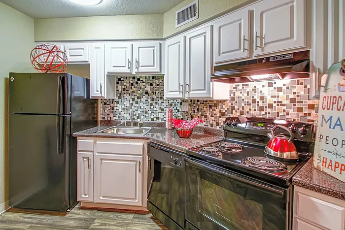 Stylish kitchen with sleek black appliances, white cabinets, and mosaic tile backsplash.