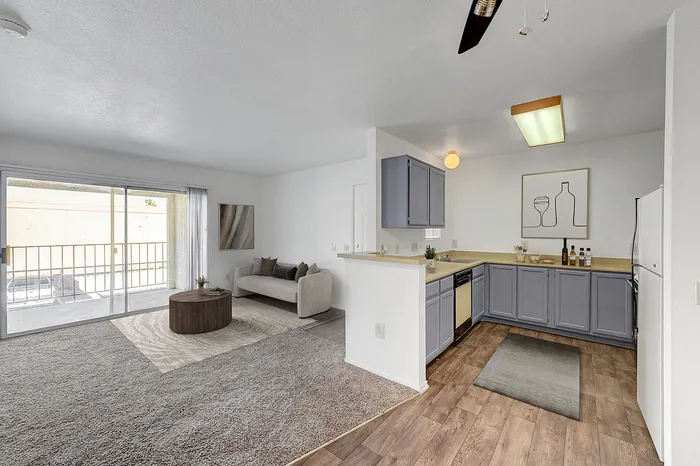 Bright open-concept living area with kitchen, cozy seating, and large sliding glass doors to a balcony.