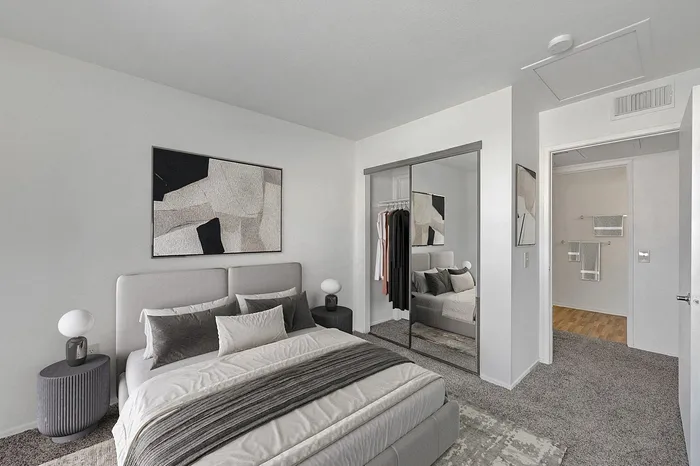 Modern bedroom with sleek mirrored closet doors, a plush double bed, and minimalist decor.