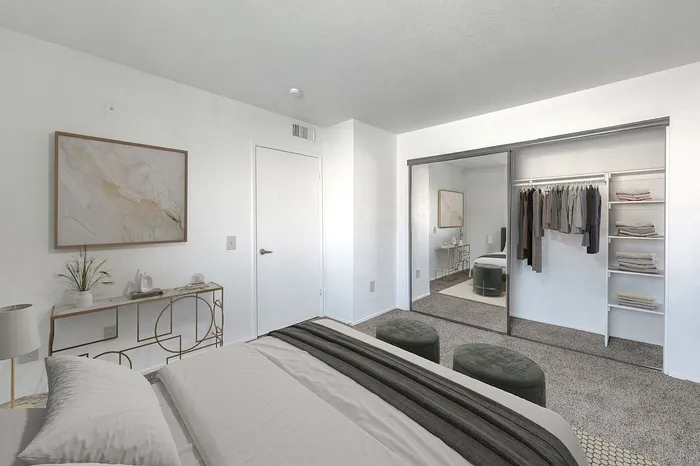 Sophisticated bedroom with modern furnishings, large mirrored closet, and decorative art on the wall.